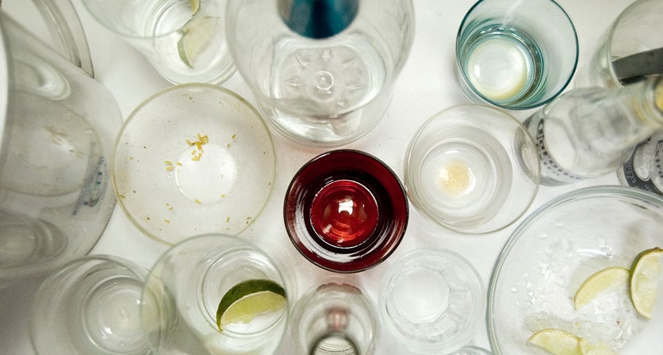 Empty glass bottles of cheap alcohol fill a countertop