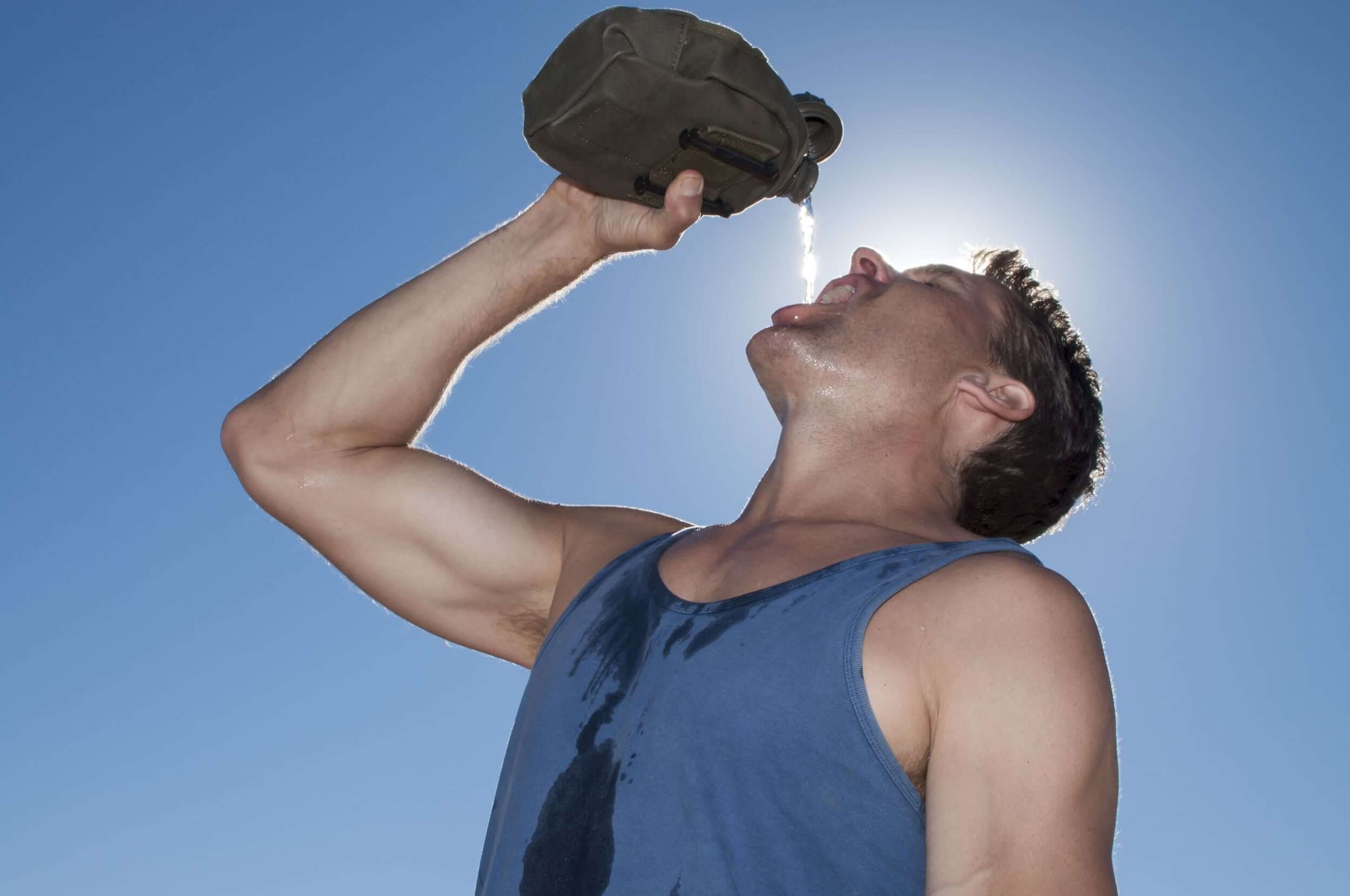 A thirsty man guzzles water from a dehydration canteen.