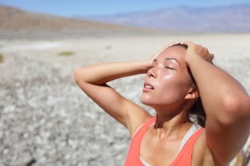 A woman basks in sunlight while standing outside